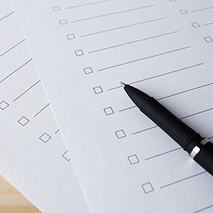A checklist and pen on table symbolize organization